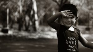 Black and white image with young boy holding his arm up.