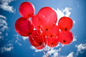 Cluster of red balloons outside.