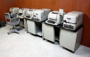 Row of teleprinters against a wall.