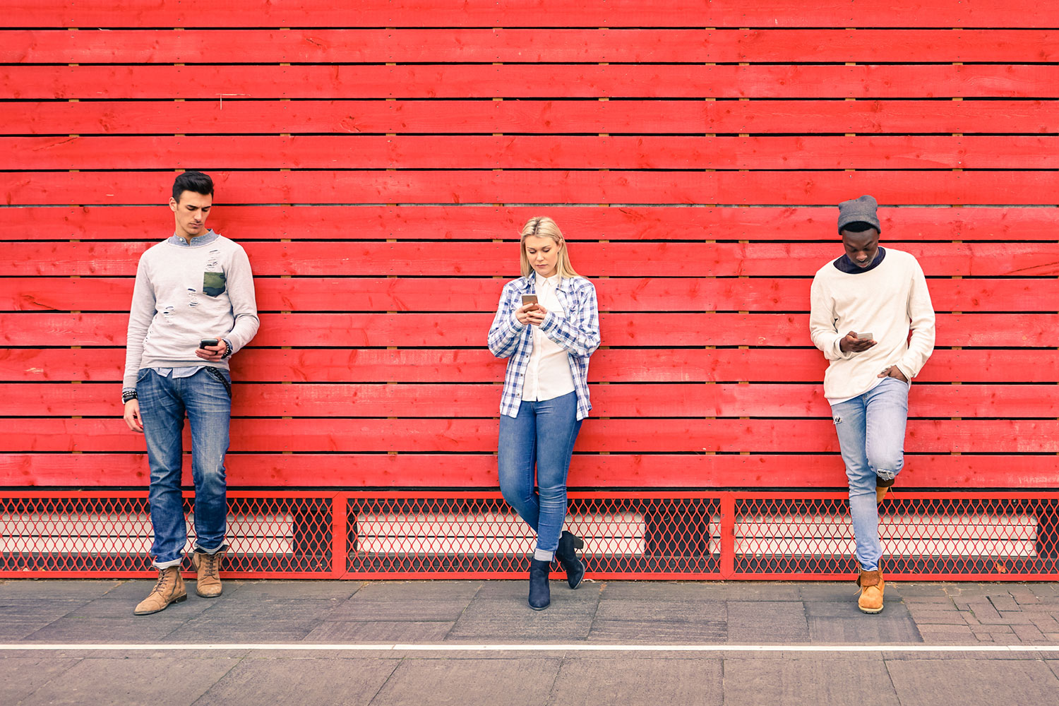 api_guys 3 people on cell phone in front of a red wall