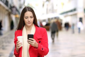 Woman in red with cell phone and coffee.