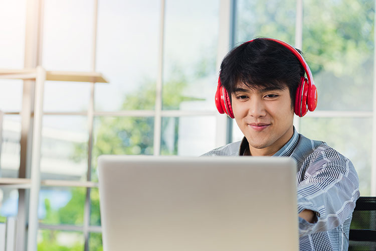 Man with red headphones on computer.
