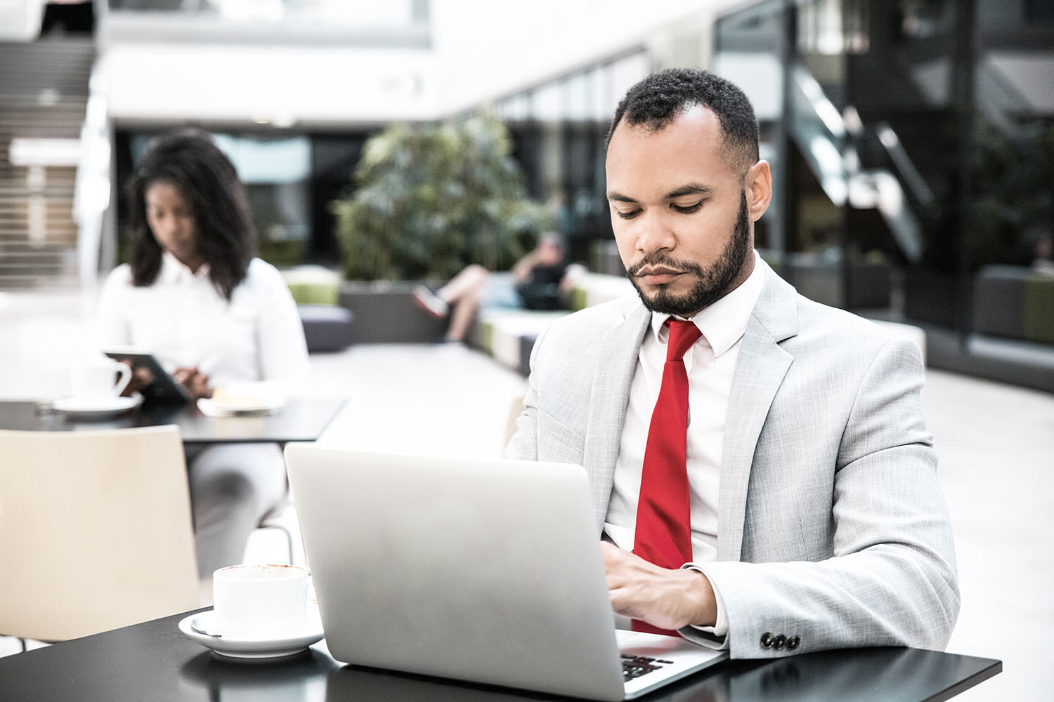 Man with red tie on a laptop.