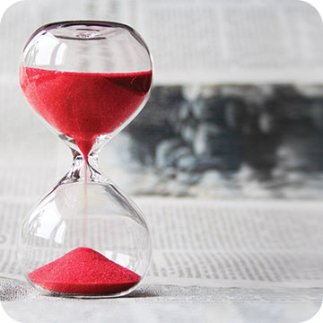 Hourglass with red sand inside.