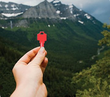 Red key being held in front of mountains