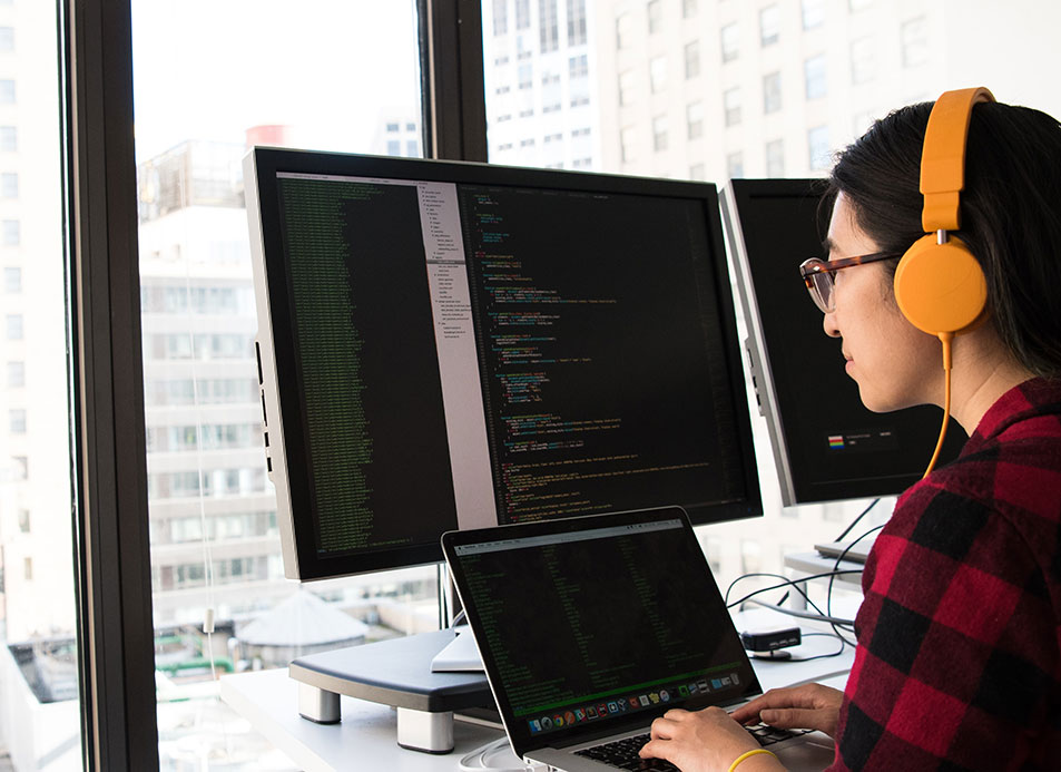 women on computer wearing orange headphones