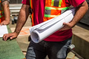 Construction foreman holding a roll of blueprints on the job site