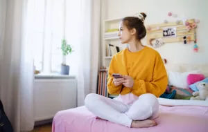 Women in yellow shirt sitting on bed