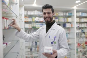 pharmacist standing by pills on shelf